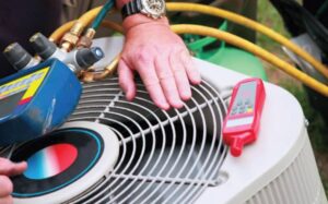 A Cranney Home Services technician inspects an outdoor AC unit, with professional tools and gauges arranged on top.