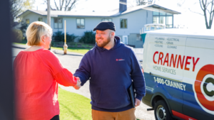 Cranney Home Services employee shaking hands with happy customer in her front yard.