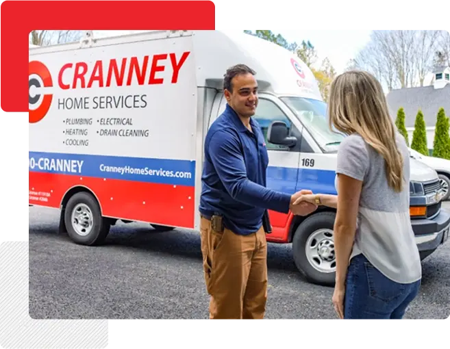 A Cranney Home Services technician shakes hands with a woman in front of a Cranney service van parked in a driveway.