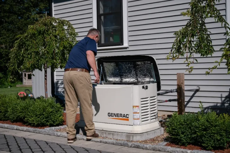 A man inspects an outdoor Generac generator installed beside a house with gray siding and shrubs in the yard.