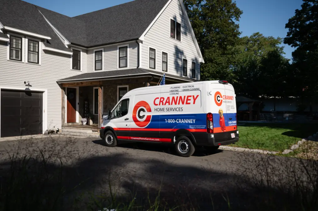 A Cranney Home Services van is parked in the driveway of a two-story house on a sunny day.